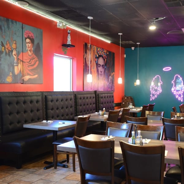 Lomeli's Mexican Bar and Grill interior with Frida Kahlo art, black booths, and neon angel wings.