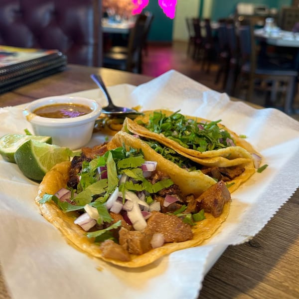 Two Lomeli's Mexican Bar and Grill tacos with meat, cilantro, onions, lime, and salsa.