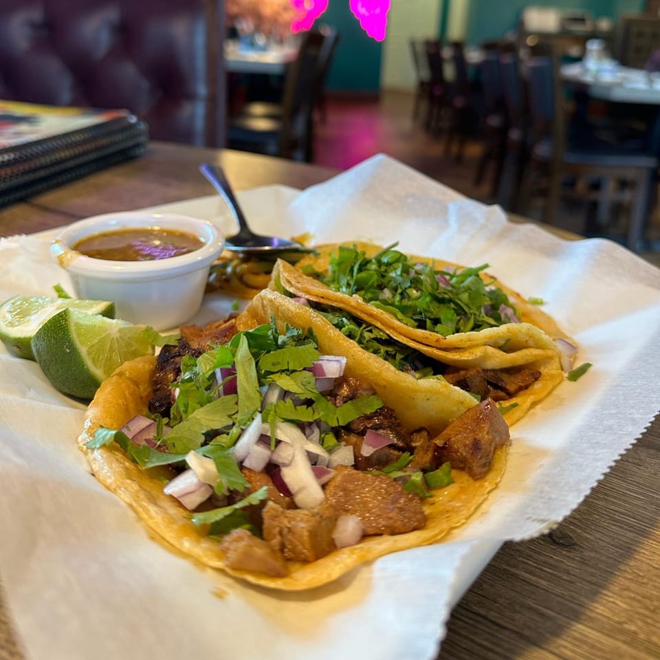 Two Lomeli's Mexican Bar and Grill tacos with meat, cilantro, onions, lime, and salsa.