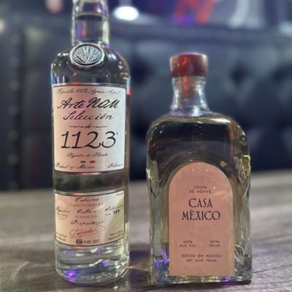 Two bottles of tequila, Arte NOM Selección 1123 and Casa México, on a dark surface.
