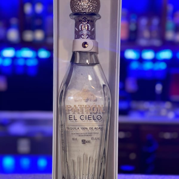 A bottle of Patrón El Cielo tequila in a white box, with a blue lit background.