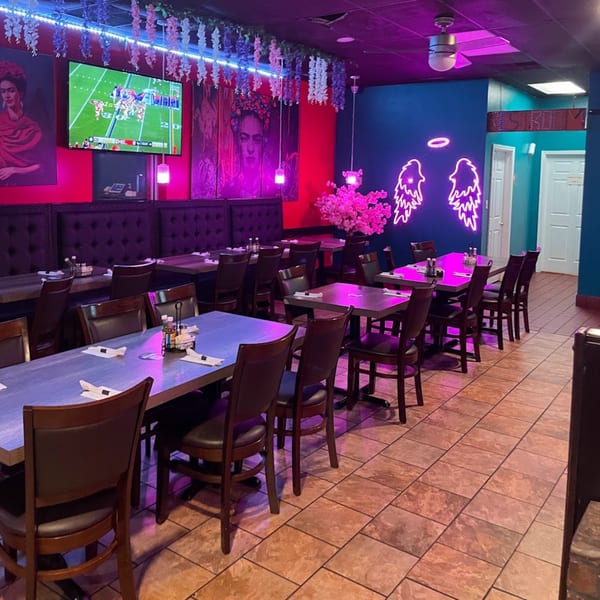Lomeli's Mexican Bar and Grill dining room with purple lighting, Frida Kahlo art, and neon angel wings.