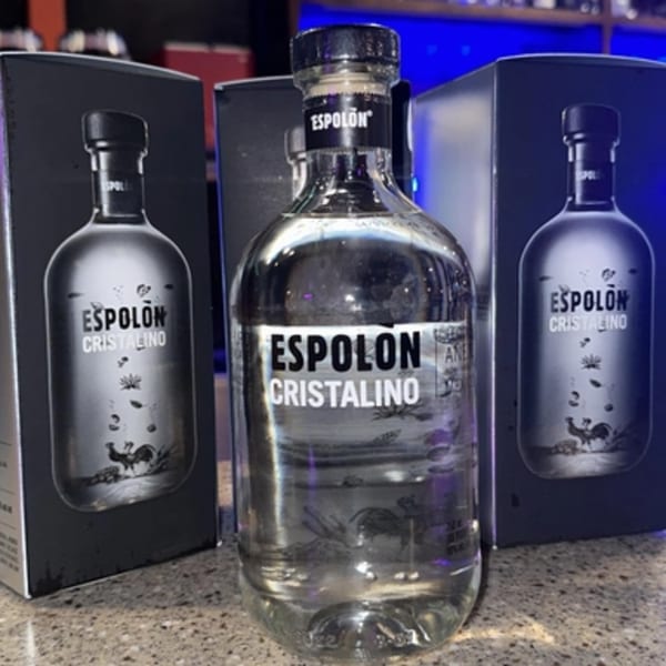 Three bottles of Espolon Cristalino tequila, one in front and two in boxes behind it.