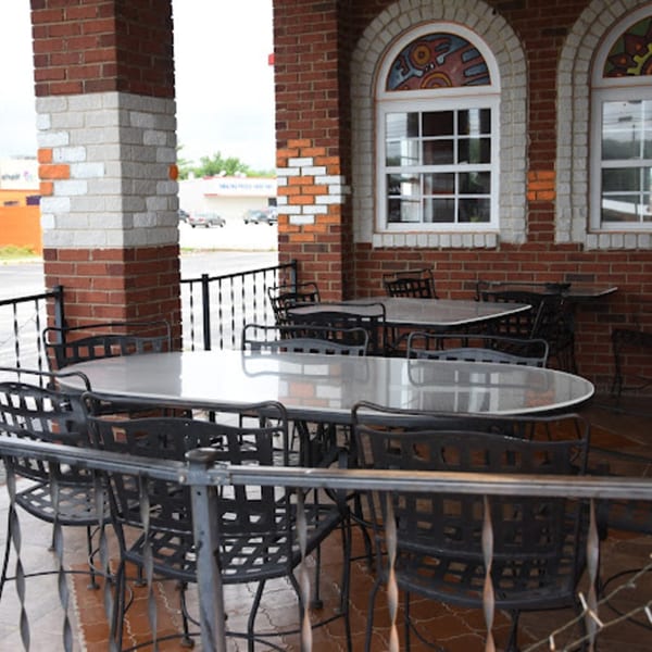 Outdoor patio of Lomeli's Mexican Bar and Grill with tables, chairs, and brick architecture.