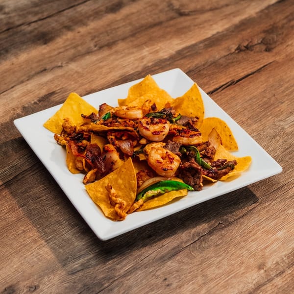 Lomeli's Mexican Bar and Grill's nachos with shrimp, steak, and green peppers on a white plate.