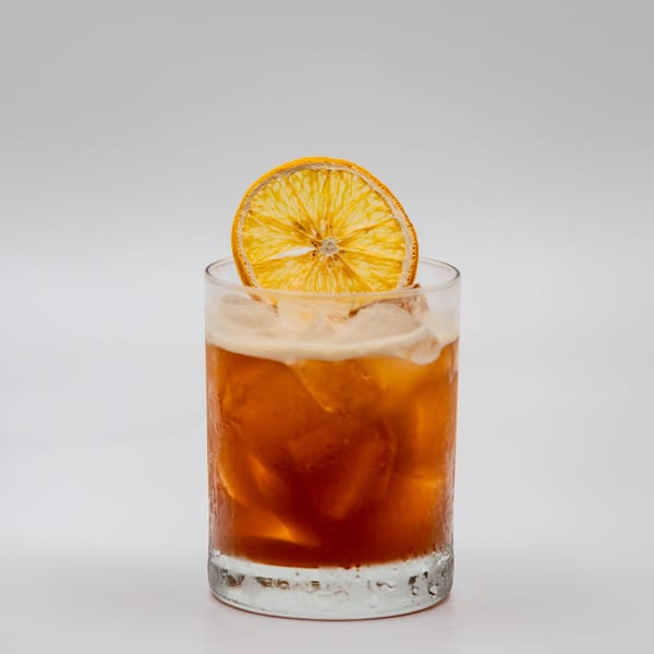 A refreshing iced tea or cocktail with a dried orange slice garnish, served in a clear glass.