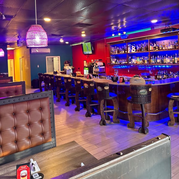 Lomeli's Mexican Bar and Grill interior with a vibrant blue-lit bar, stools, and booth seating.
