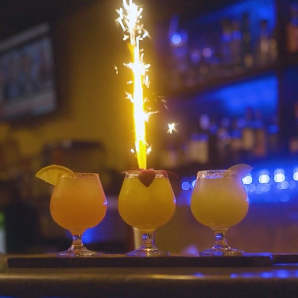 Three Lomeli's Mexican Bar and Grill cocktails on a bar, one with a sparkler.