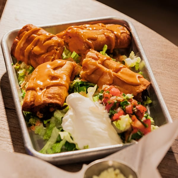 Four Lomeli's Mexican Bar and Grill enchiladas topped with sauce, lettuce, pico de gallo, and sour cream.