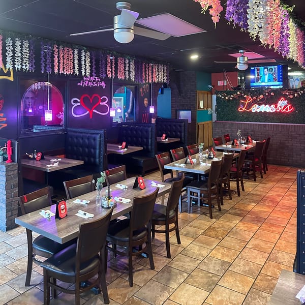 Interior of Lomeli's Mexican Bar and Grill with tables, booths, neon signs, and floral decorations.